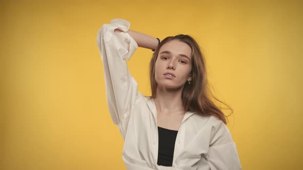 Portrait of a 20s Caucasian Woman Smiling at Camera on a Bright Yellow Background alt