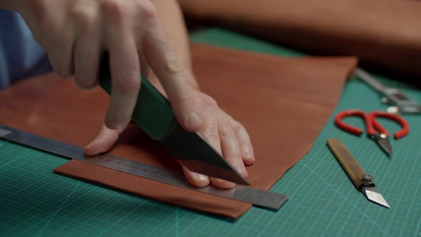 Artisan Cutting Off Leather Detail Checking Quality of Edges Indoors alt