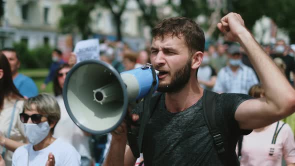 Aggressive protester with bullhorn on rally. Angry riot activist with megaphone. alt