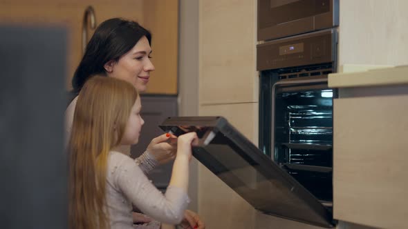 Charming Caucasian Mother and Daughter Opening Brand New Oven in Store Talking in Slow Motion alt