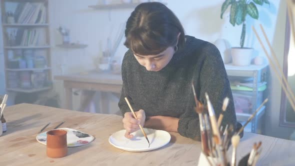 Woman painting on the cermaic plate