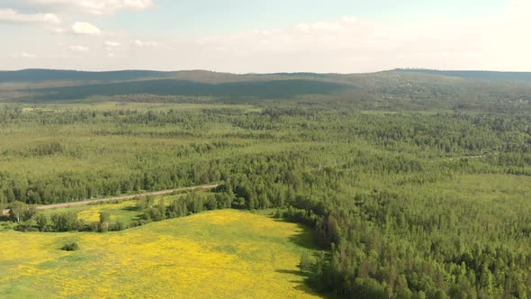 Aerial View From Drone of Country Road and Yellow Meadow Among Forest and Hill