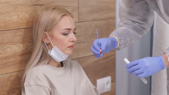 Professional Laboratory Assistant in Protective Suit Takes Swab From Nose of Sick Female Patient at