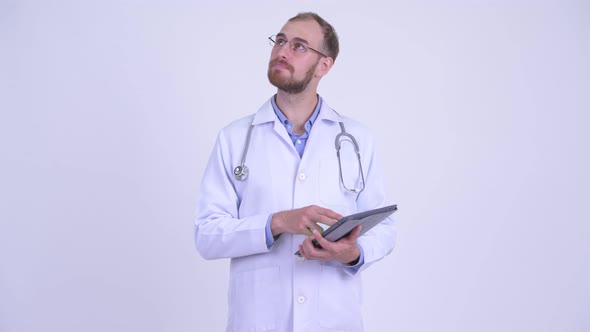 Happy Bearded Man Doctor Thinking While Using Digital Tablet