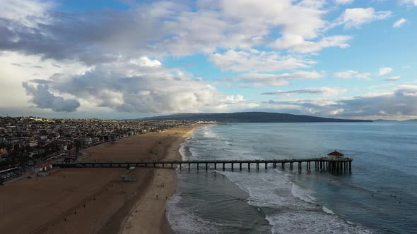 View of a pier with a house on the coast in front of a mountain overlooking the sea, zoom. Drone sun alt