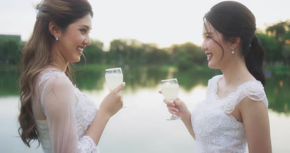 Asian Lesbian Couple Enjoying Champagne On Their Wedding Celebration. alt