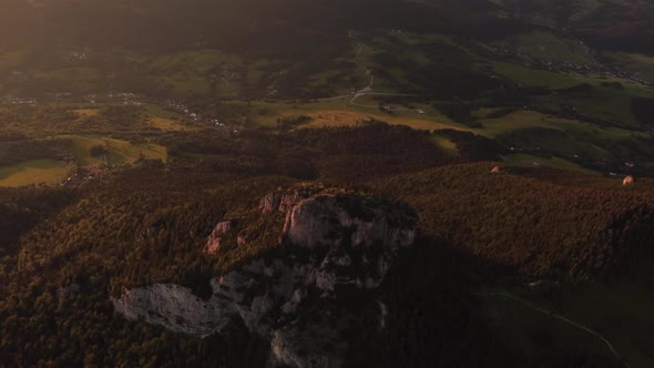 Aerial View of Rocky Peak Covered with Trees in Golden Sunlight at Sunset