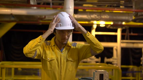 Young Man in a Yellow Work Uniform, Glasses and Helmet in Industrial Environment,oil Platform or alt
