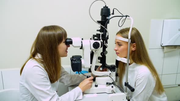Woman checks her eyesight with optical equipment alt