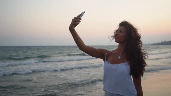 Young Smiling Woman Using Smartphone and Taking Selfies on Beach