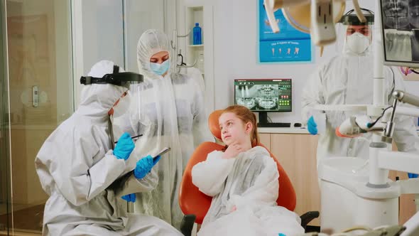 Dentist Doctor in Coverall Talking with Girl Patient Before Examination alt