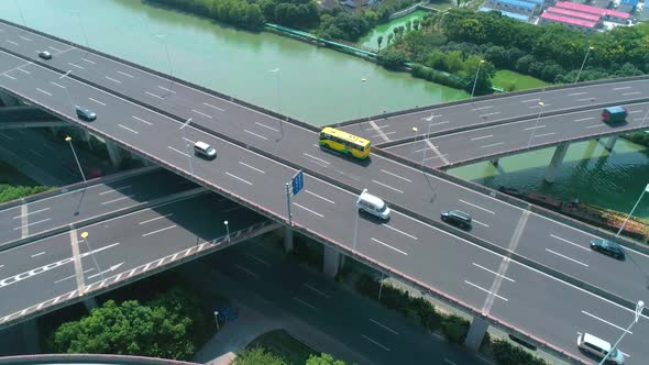 Aerial Tilt View of a Highway Overpass Multilevel Junction with Fast Moving Cars Surrounded By Green alt