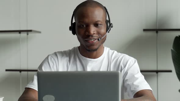 A Black Man is a Customer Service Operator with a Handsfree Headset Working in an Office alt