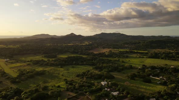 Mountainous landscape between central American farmland and the pacific ocean during sunset. Aerial alt