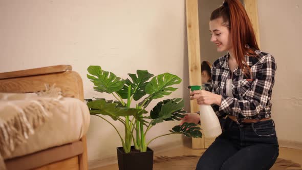 A young beautiful woman watering the plant. alt