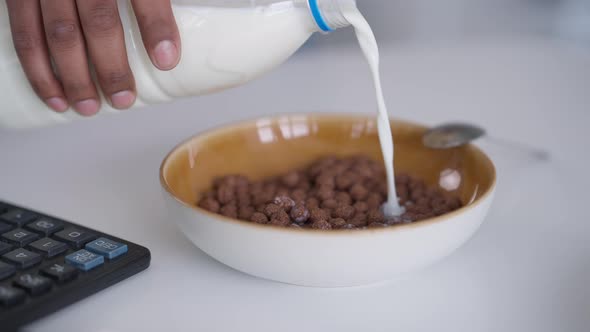 Closeup of Male African American Hand Pouring Milk in Bowl with Cocoa Balls alt