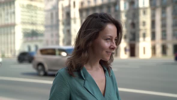 Charming Middle-aged Woman Is Walking on Wide Street of Big City in Summer Day, Smiling To Camera alt