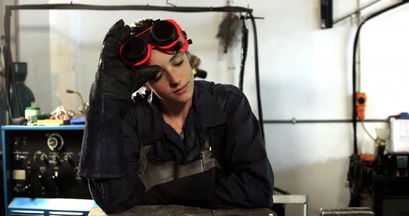 Female welder leaning in workshop alt