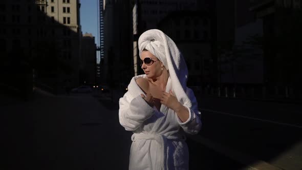 Girl in Bathrobe and Towel on Head in a City Street