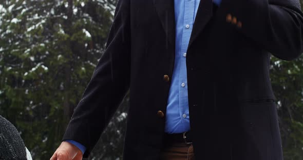 Man talking on the phone and charging the electric car on a snowy day alt
