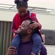 Smiling African father carries his daughter around his neck near the trailer - VideoHive Item for Sale