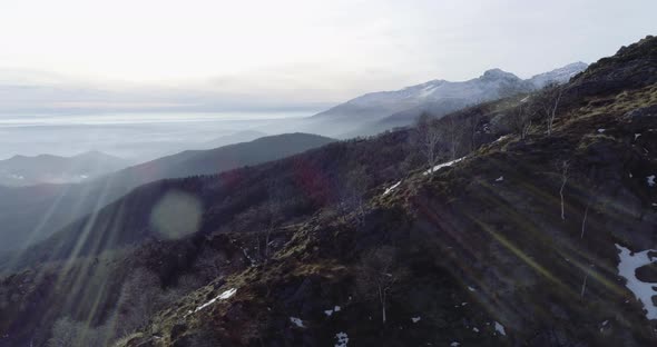 Side Aerial Drone Flight Establisher Over Forest Woods with Mountains and Planes in Winter