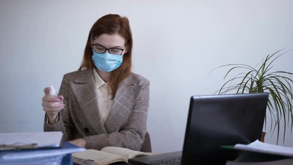 Coronavirus Pandemic, Young Businesswoman in Medical Face Mask Uses an Antiseptic To Prevent Viruses alt