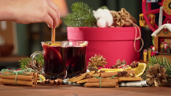 Putting Cinnamon Into Hot Wine in Glass Mugs Gluhwein Closeup alt