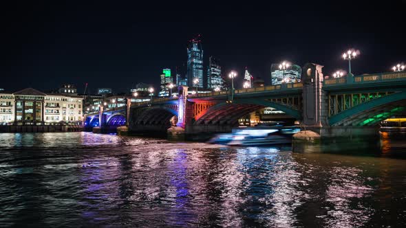 Illuminated Southwark bridge at night and City skyline in background, London, UK alt