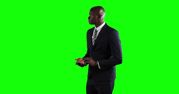 an African American man in suit using a phone in green background