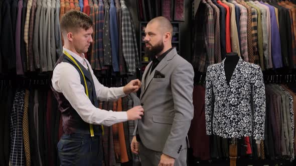 Slow motion of handsome man choosing a suit design with tailor in atelier alt