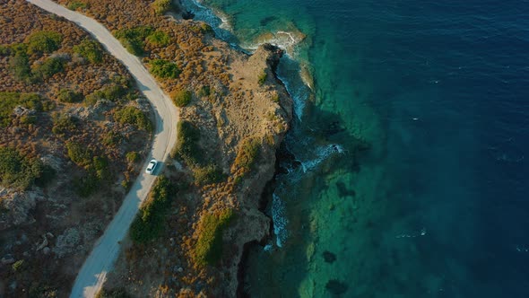 Aerial Top View Car Driving on Coastal Road Sea Waves Washing Rocky Coast alt
