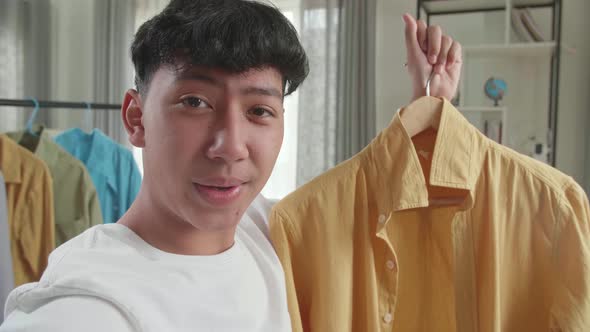 Close Up Of Asian Man Online Seller Recommending A Shirt And Recording Video While Selling Clothes alt