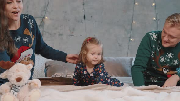 A Happy Family Lies on the Bed and Plays with Their Little Daughter alt