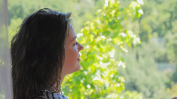 Relaxing Woman on Balcony Listening to Music on Phone alt