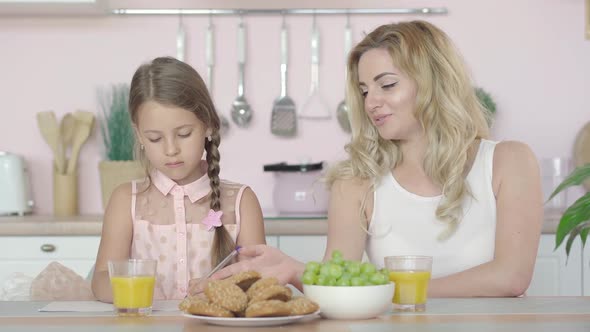 Beautiful Young Mother Helping Daughter with Homework in the Morning. Portrait of Happy Caucasian alt