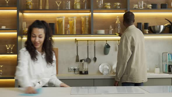 Young Couple Cleans Modern Kitchen with Sponge Together alt