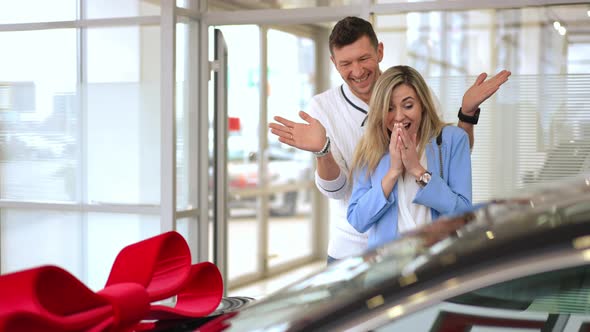 Loving Man Buying New Automobile for Woman in Car Dealership Surprising Partner alt