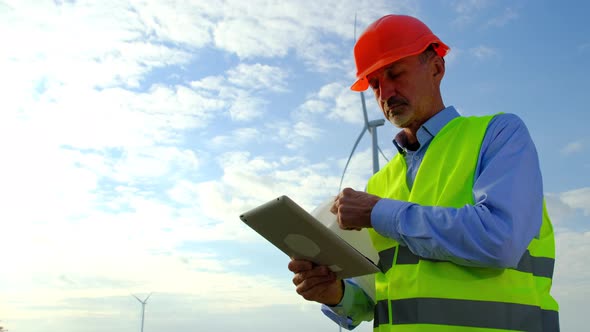 Engineer Verifies Documentation of Project Near Windmills alt