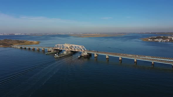 A high angle shot of an elevated train track crossing over the bay in Queens, NY. The camera trucks alt
