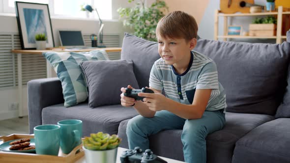 Joyful Child Enjoying Video Game in Apartment Having Fun Relaxing on Sofa alt