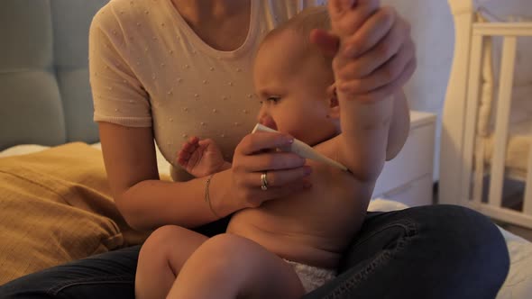Little Baby Boy Screaming and Crying While Mother Measuring His Body Temperature with Thermometer alt