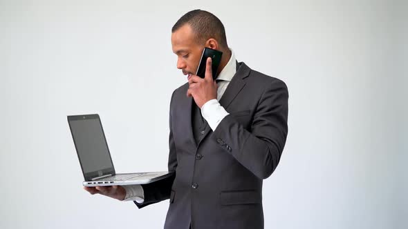 Professional African-american Business Man Holding Laptop Computer and Talking on the Phone alt