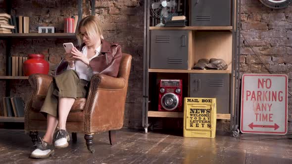 General Plan A Young Business Woman Blonde With Glasses Looking Down Using A Smartphone alt