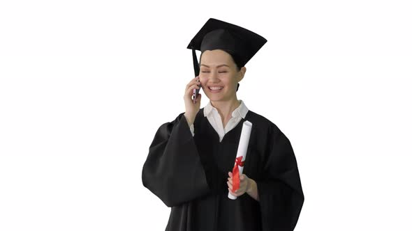 Emotional Female Student in Graduation Robe Talking on the Phone Holding Diploma on White Background