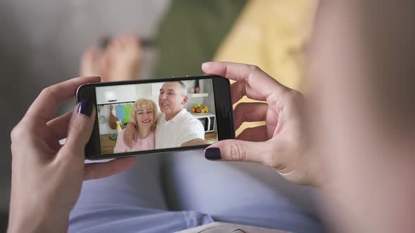 Daughter Woman Talking To Happy Elderly Parents Through Facetime on Smart Phone alt