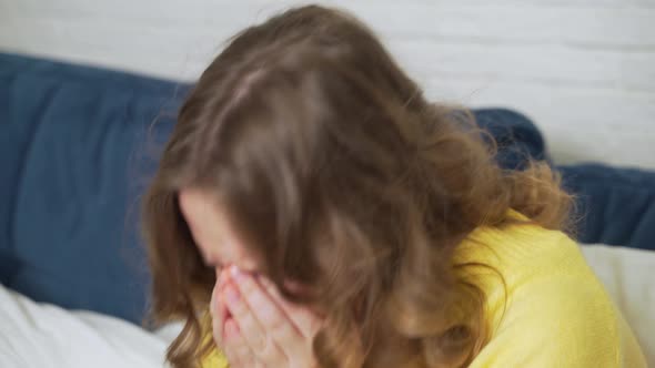 Woman in Sweater Sits on Bed and Coughs and Sneezes
