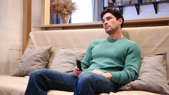 Man Watching TV Changing Channels with Remote Control alt