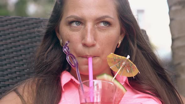 Happy Woman with Loose Hair Tastes Cocktail and Smiles alt