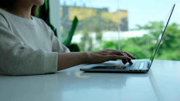 Closeup a woman working and typing on laptop computer keyboard on the table